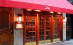 Cozy restaurant entrance with red awning and wooden doors.