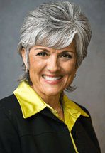 Smiling older woman with short gray hair and a yellow-collared shirt.