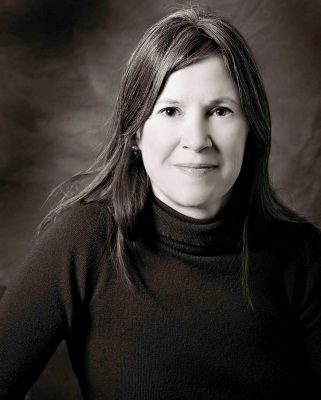 Black-and-white portrait of a woman with long hair in a dark turtleneck sweater.