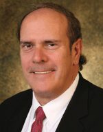 Professional headshot of a middle-aged man in a suit and tie.