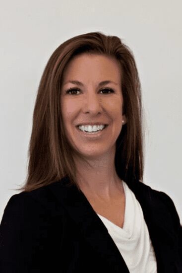 Smiling woman with long brown hair in professional attire.
