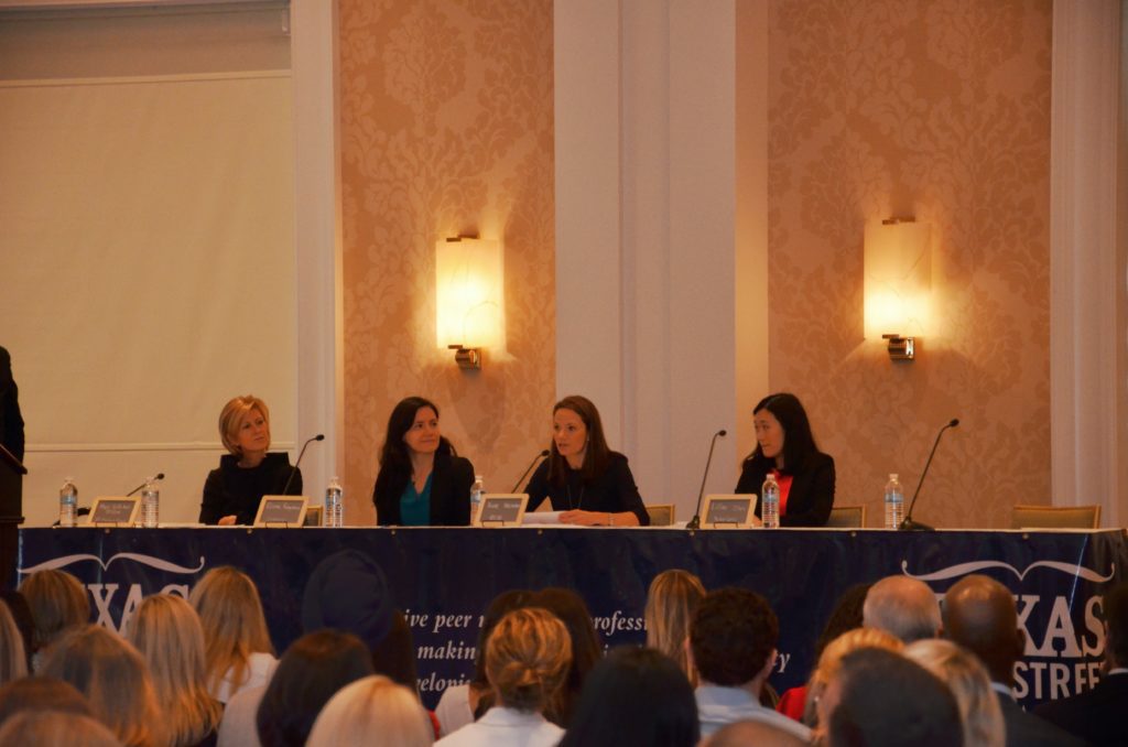 Panel discussion with four women speaking to an audience in an elegant room.