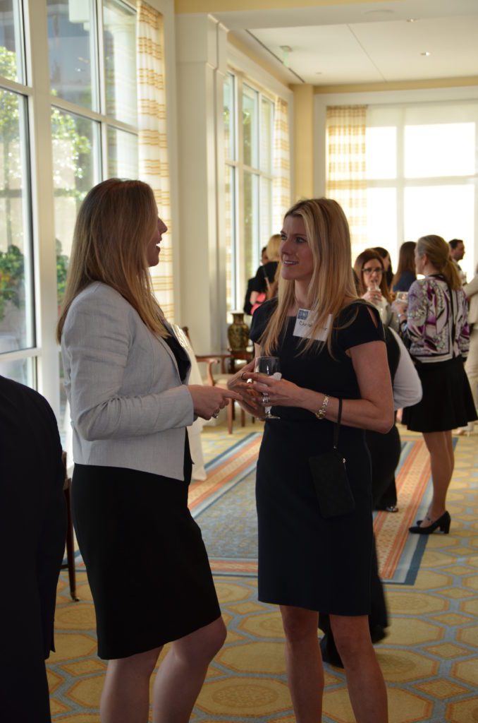Two women in conversation at a social event, holding drinks.