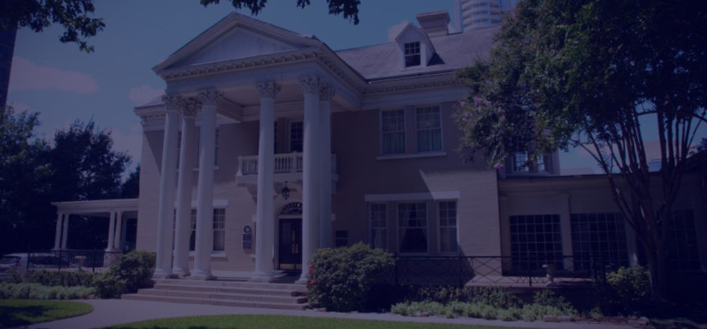 A grand historic mansion with large white columns and a brick facade.