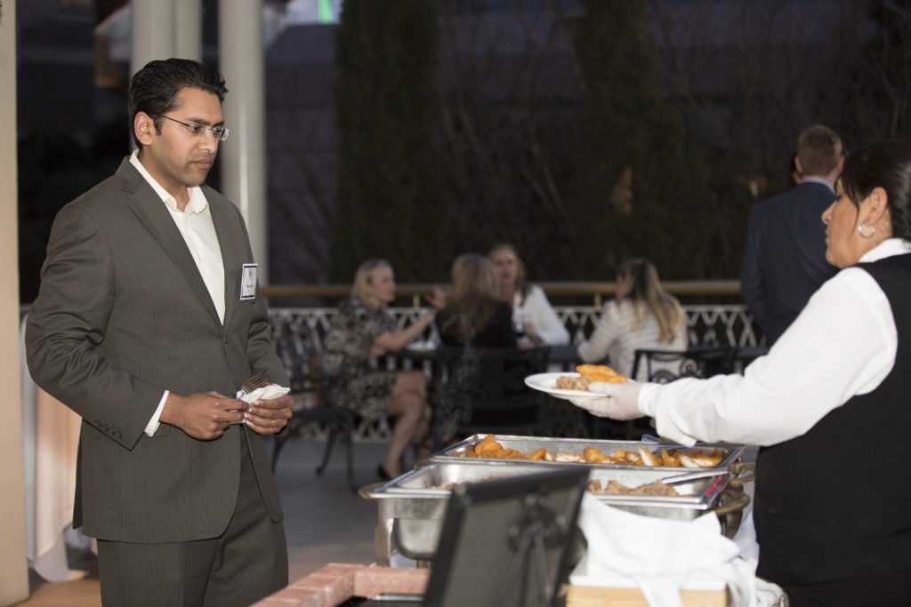 A man receiving food from a waiter at a buffet table.