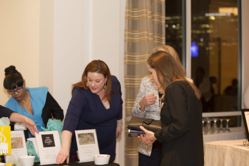 Two women engaging with items at a display table indoors.