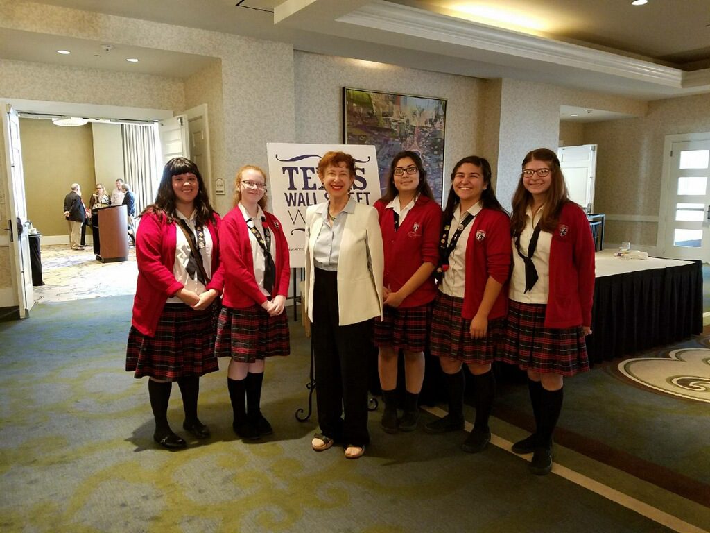 Group of six women in coordinated outfits posing indoors.