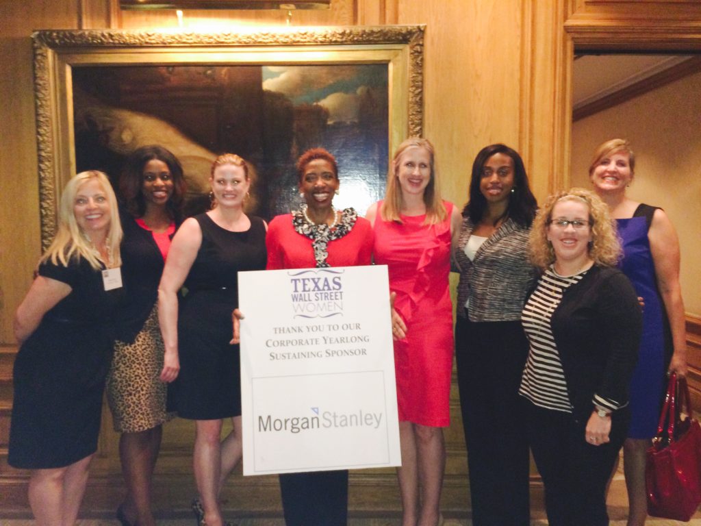 Group of women standing indoors, holding a large check from Texas Woman's University.