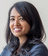 Portrait of a smiling woman with dark hair in business attire.