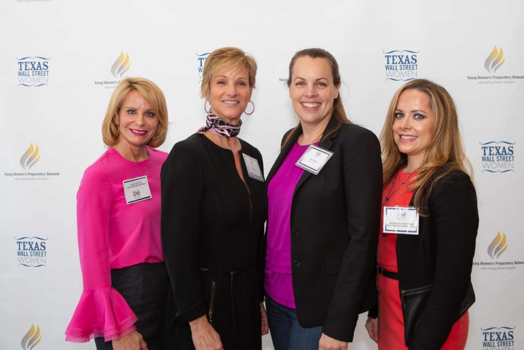 Four professional women smiling at a networking event.