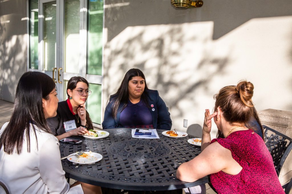 Four women having a meal together at an outdoor table.