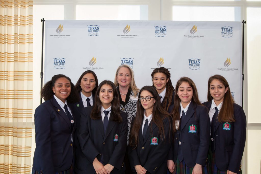 Group of young women in formal attire posing together at an event.