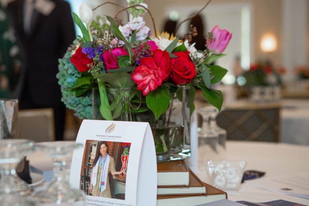 A vibrant bouquet of flowers in a glass vase on a table with a framed photo.