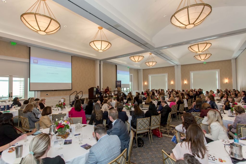 A large group attending a formal conference in a well-lit ballroom.