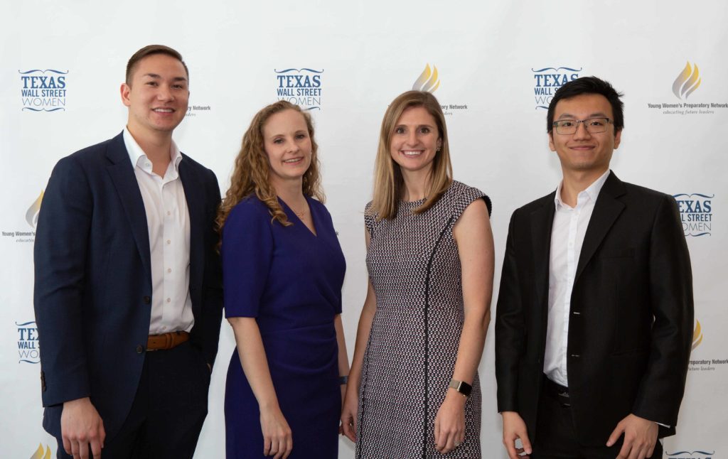 Four professionally dressed individuals posing against a white backdrop.