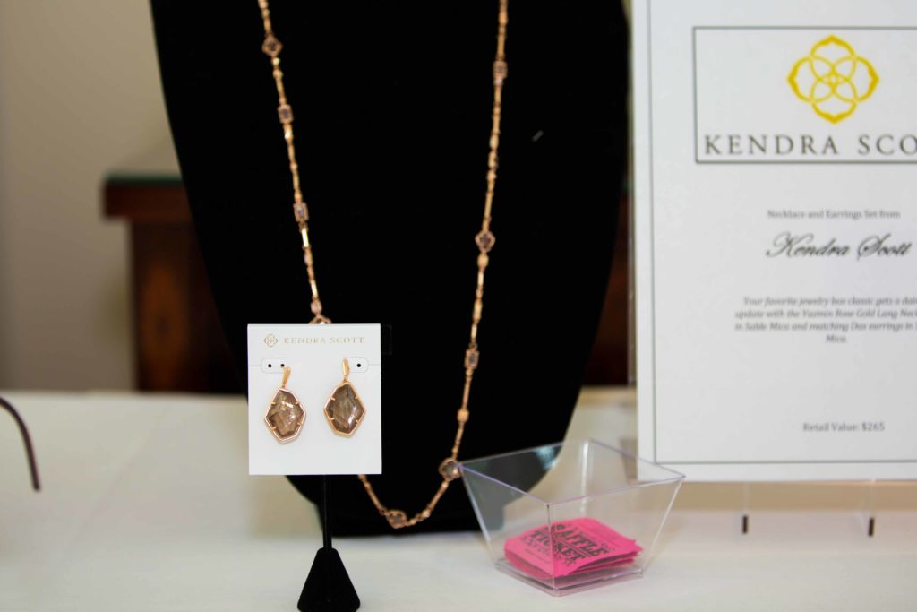 Elegant gold necklace and matching earrings displayed on a white stand.