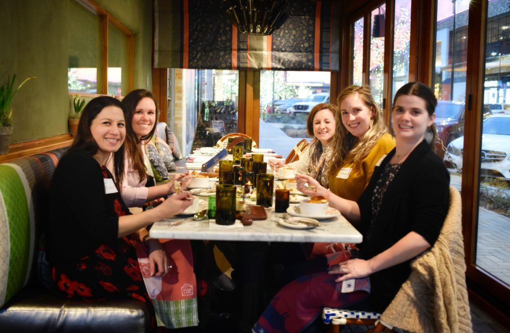 Five women enjoying a meal together at a cozy restaurant table.