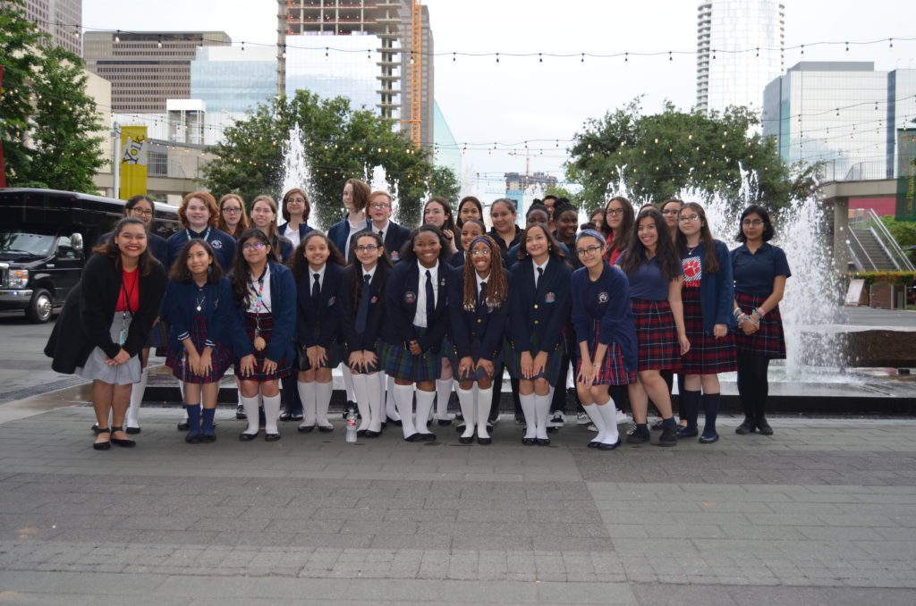 Group photo of schoolchildren in uniforms outdoors.