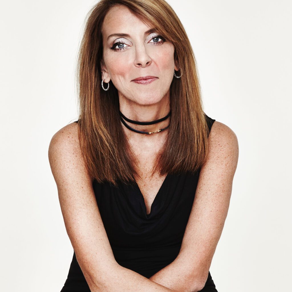 Confident woman with straight brown hair wearing a black sleeveless top.