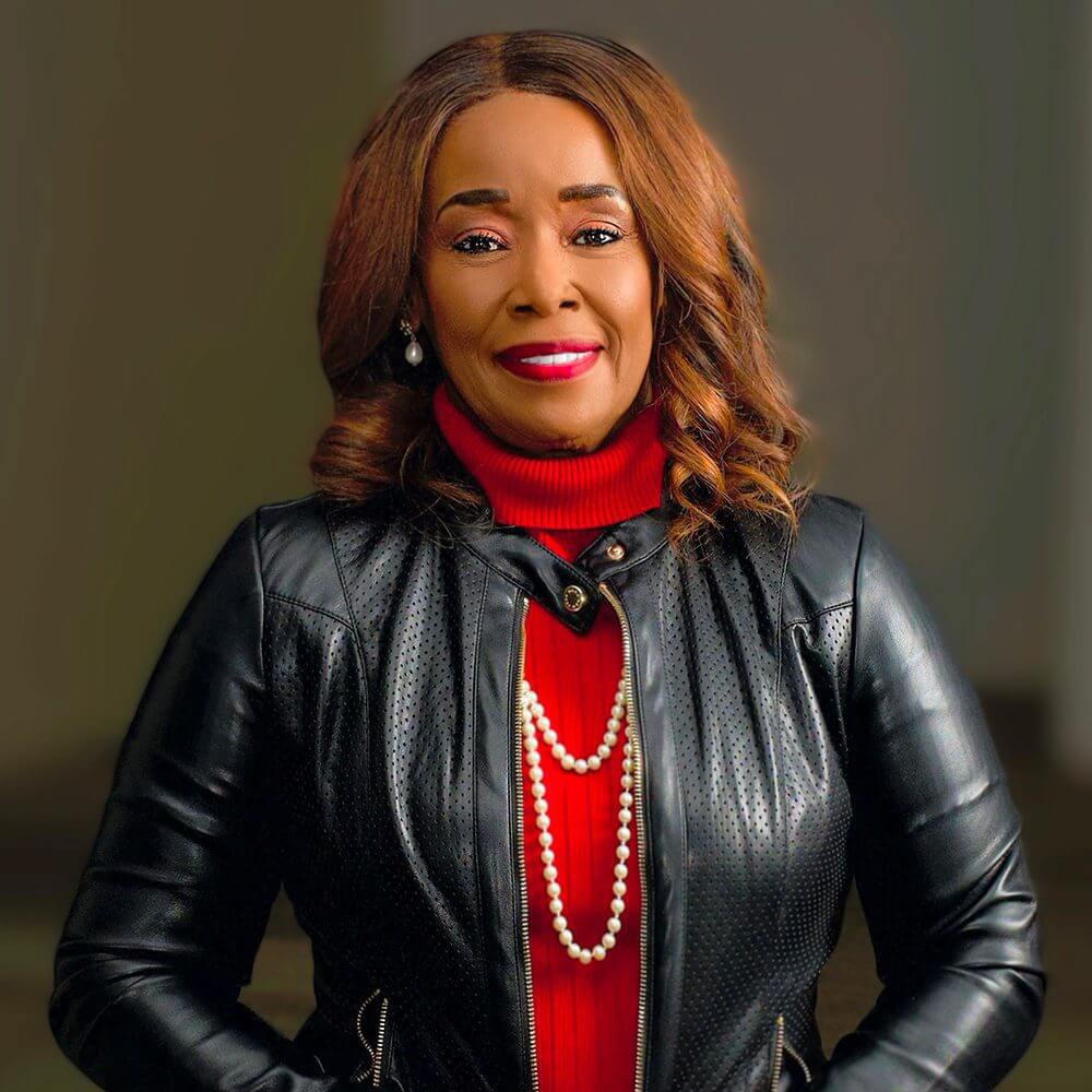 Confident woman in a red turtleneck and black leather jacket smiling.