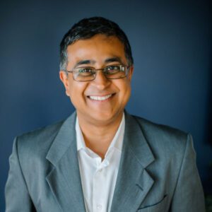Smiling man in a gray suit jacket.