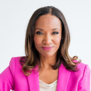 Woman in pink blazer, smiling confidently.