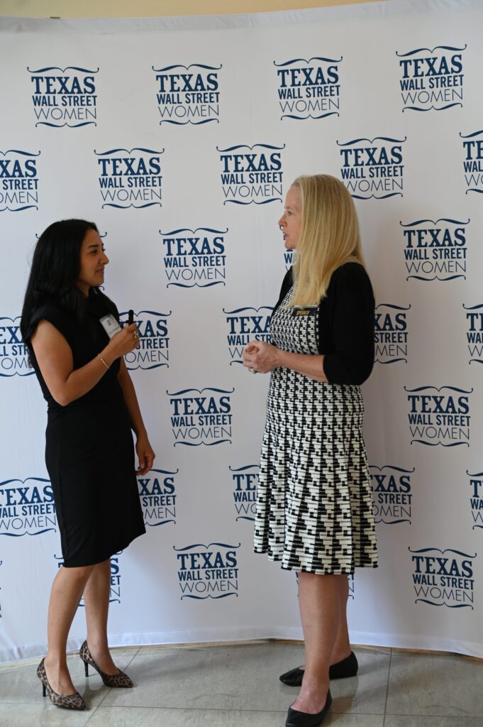 Two women conversing at Texas Wall Street event.
