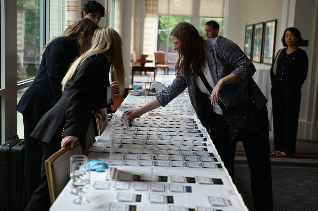 People checking name tags on a table.