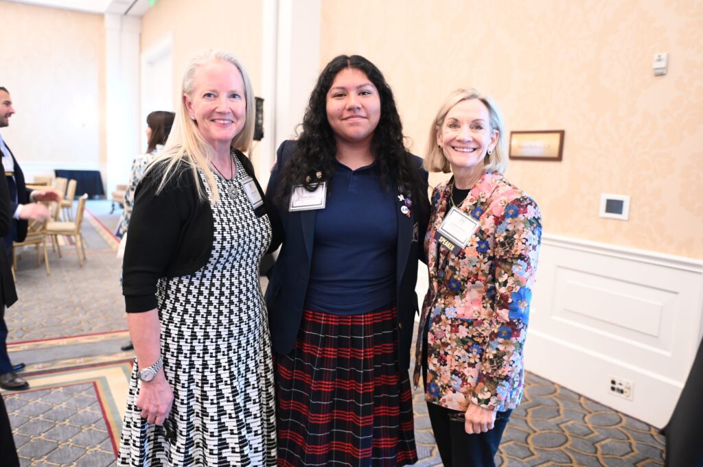 Three women posing at a formal event.
