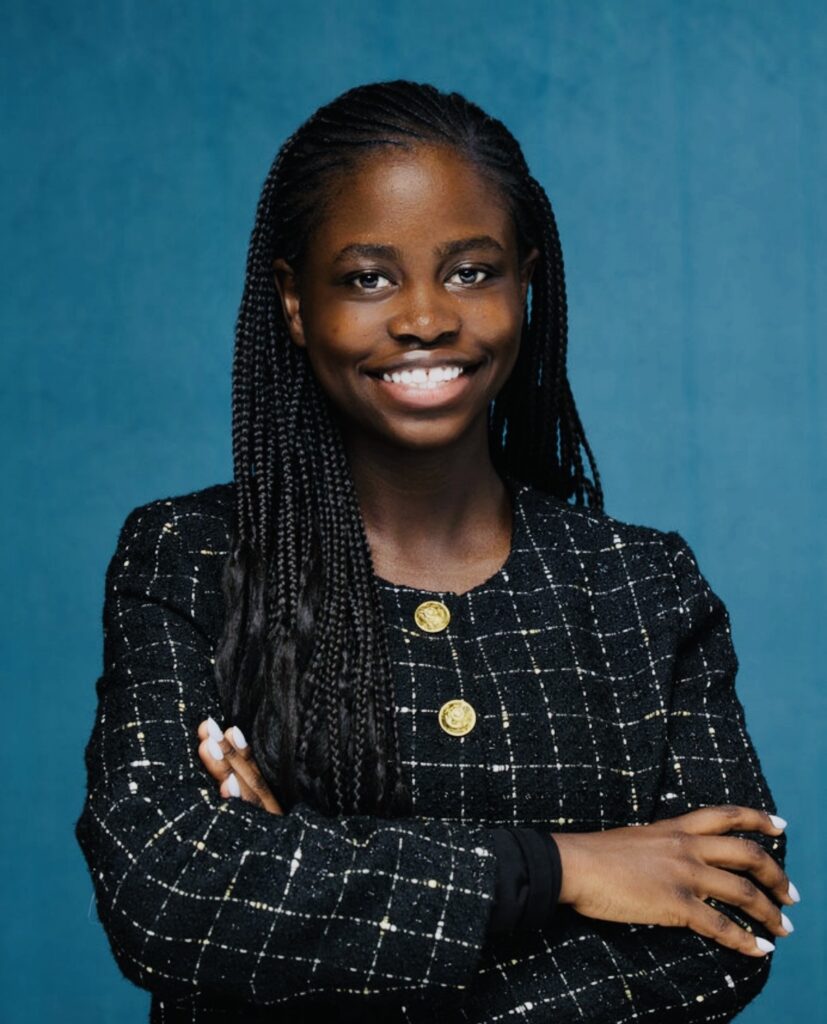 Smiling woman with braided hair, arms crossed